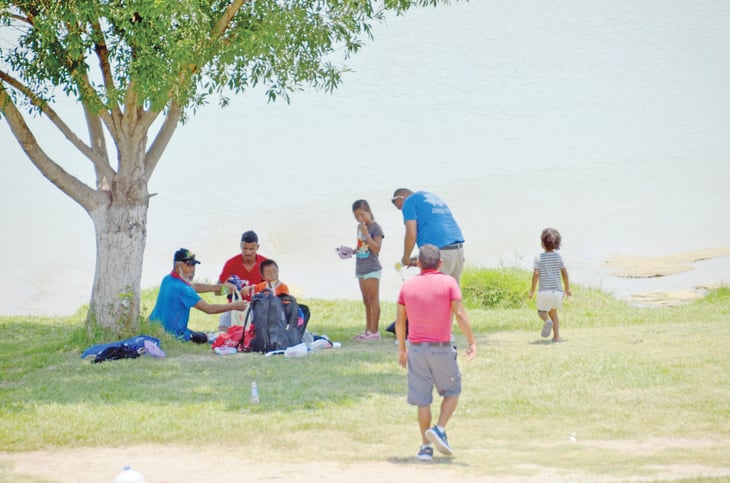 Familias de migrantes van al río Bravo a mitigar el sol
