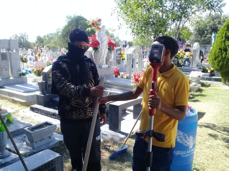 Jóvenes trabajan limpiando tumbas