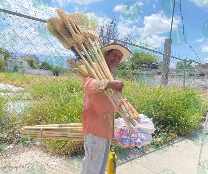 Don Sergio camina bajo los rayos del sol para vender sus escobas y trapeadores