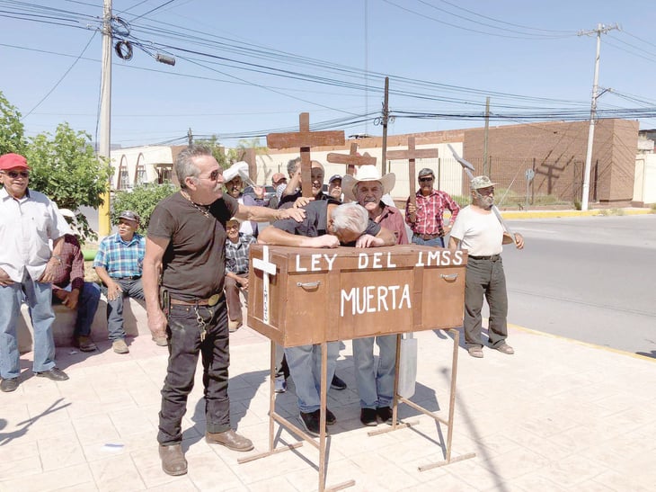 Pensionados cargan un ataúd afirmando: 'Ley del IMSS muerta'