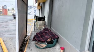 Un hombre indigente lucha por sobrevivir en el frío extremo de la ciudad.  La imagen es desgarradora: un hombre en silla de ruedas, cubierto con un cobertor