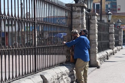 Escuchan misa sobre  la barda de la iglesia