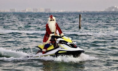 En moto y traje de baño, llega Santa Claus a playas de Cancún