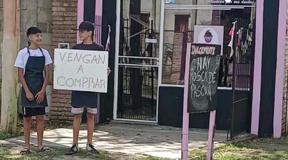 Chico apoya a su mamá con un cartel para aumentar las ventas: Este chico se instaló con un cartel frente al negocio de su mamá para aumentar las ventas