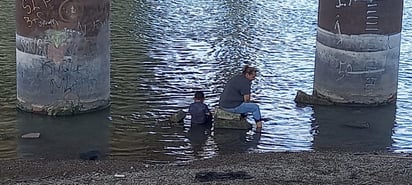 María y su hijo Lían mitigan el calor en las aguas del Bravo 