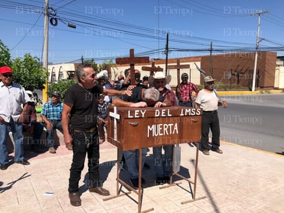 Pensionados cargan un ataúd afirmando: 'Ley del IMSS muerta'