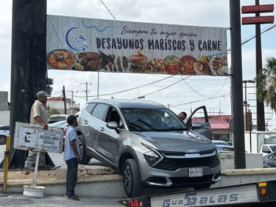 Mujer queda pendiendo en su vehículo de banqueta