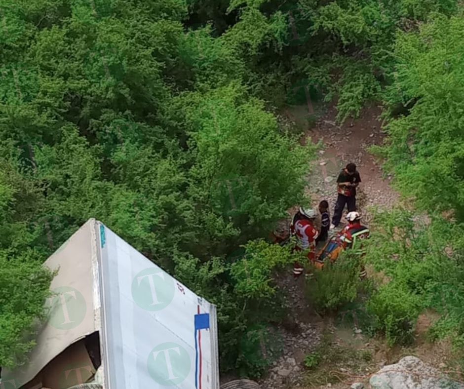 Tráiler cae de puente; socorristas tratan de ayudar al conductor.