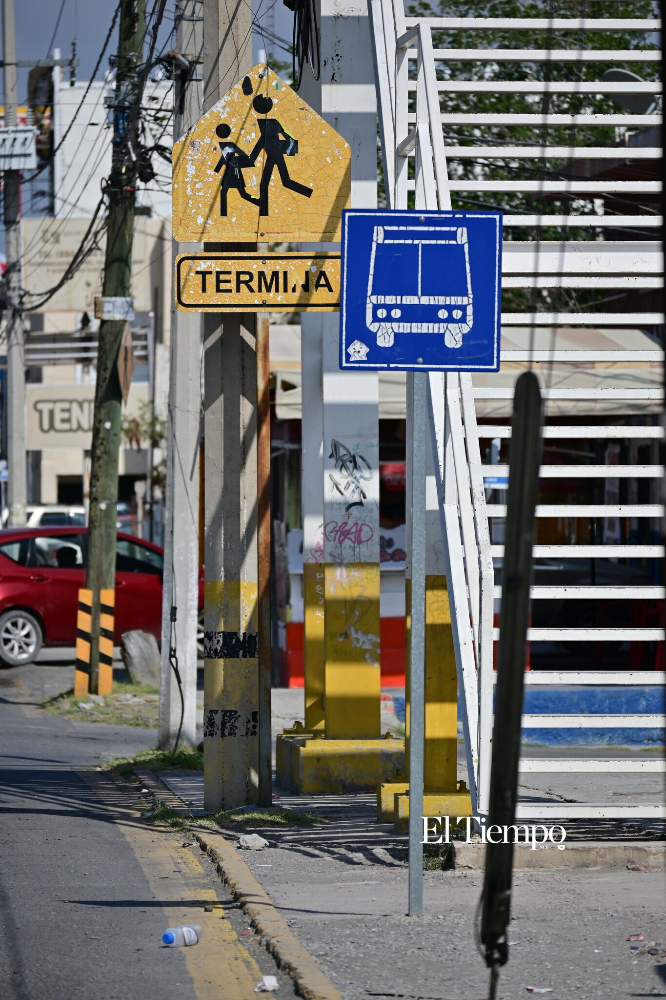Conjunto de señalamientos que indican zona escolar y parada de transporte público.