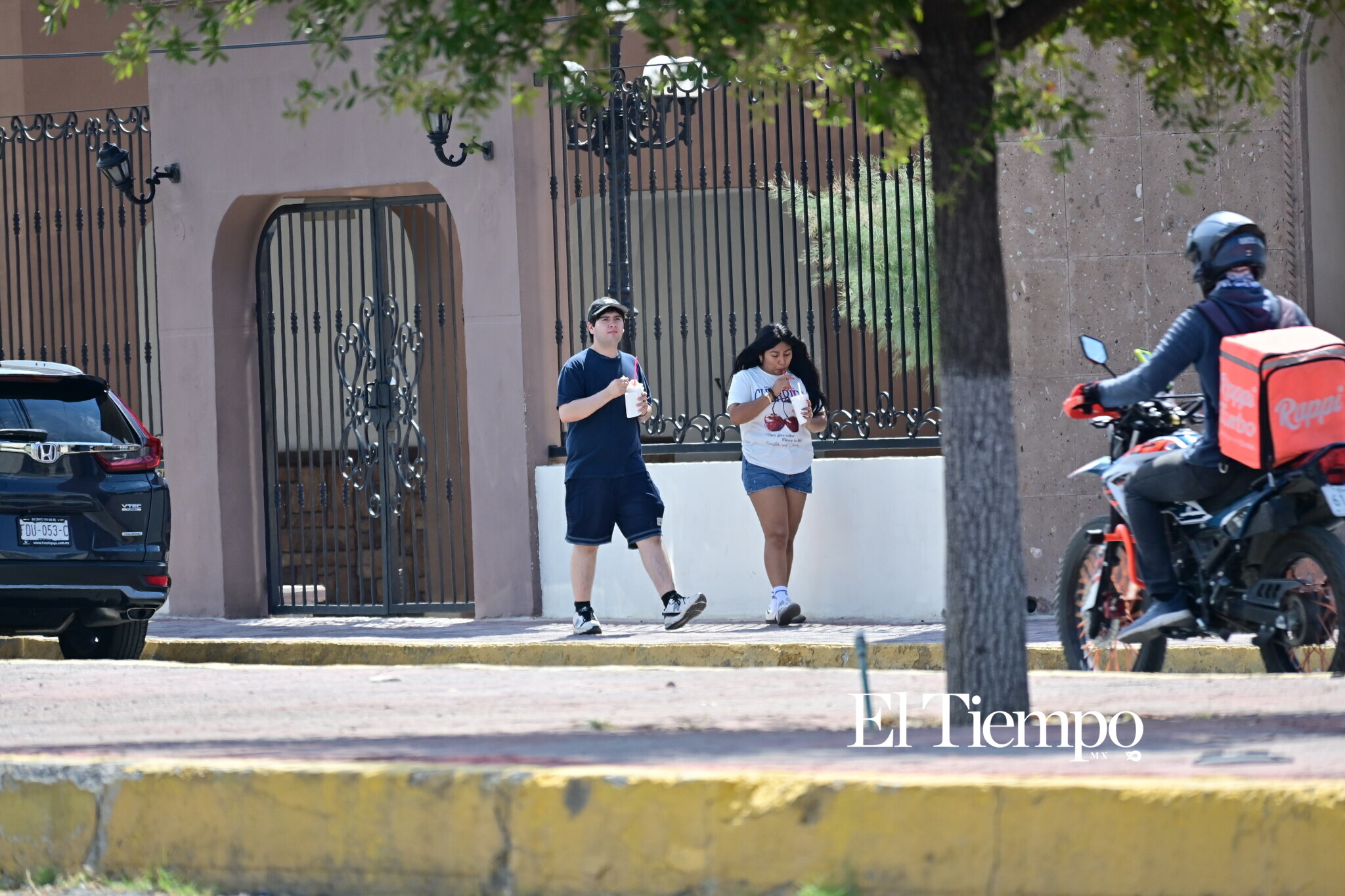 El calor lleva a dos peatones a buscar una forma de refrescarse mientras continúan su recorrido por la ciudad.