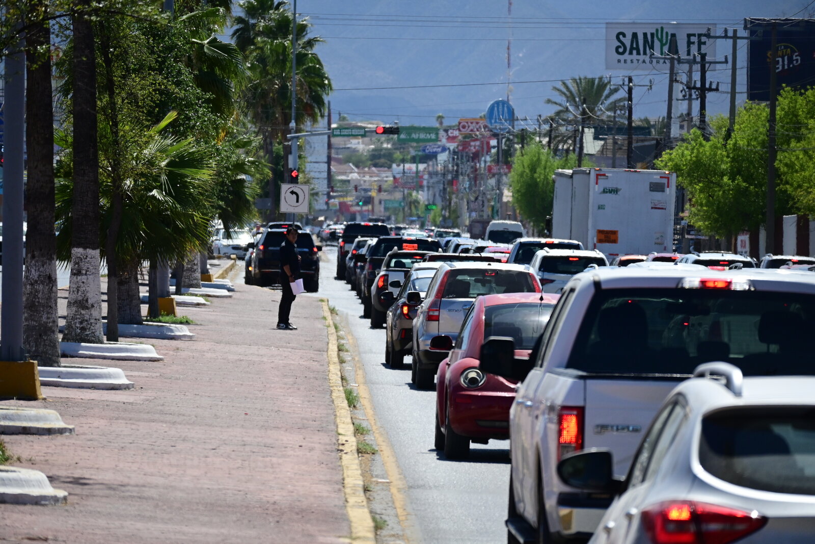 vialidad : Filas de vehículos y peatones en espera reflejan el ritmo diario del tránsito en la ciudad.